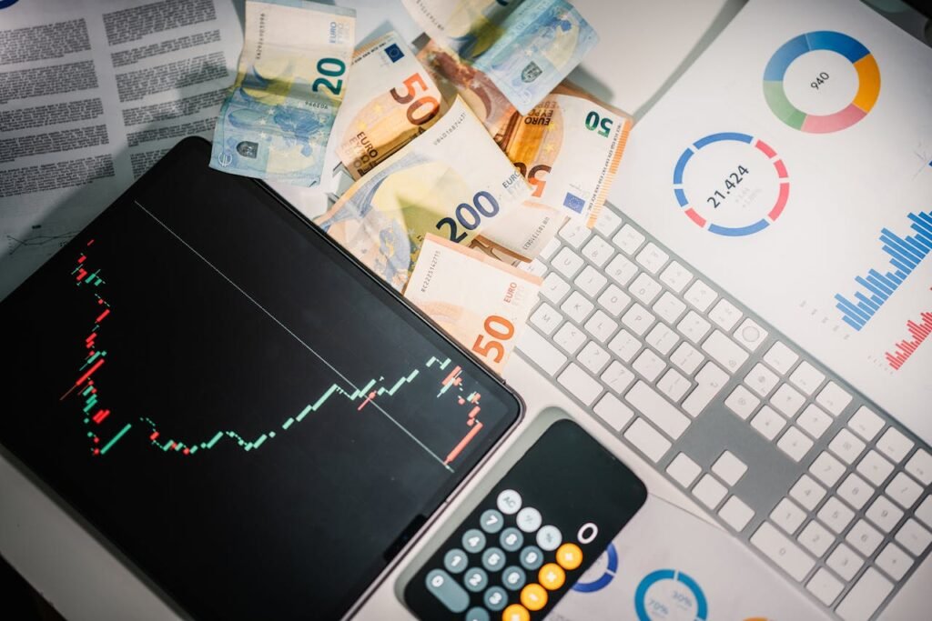 Overhead view of financial tools with Euro banknotes on a desk showing market trends and graphs.